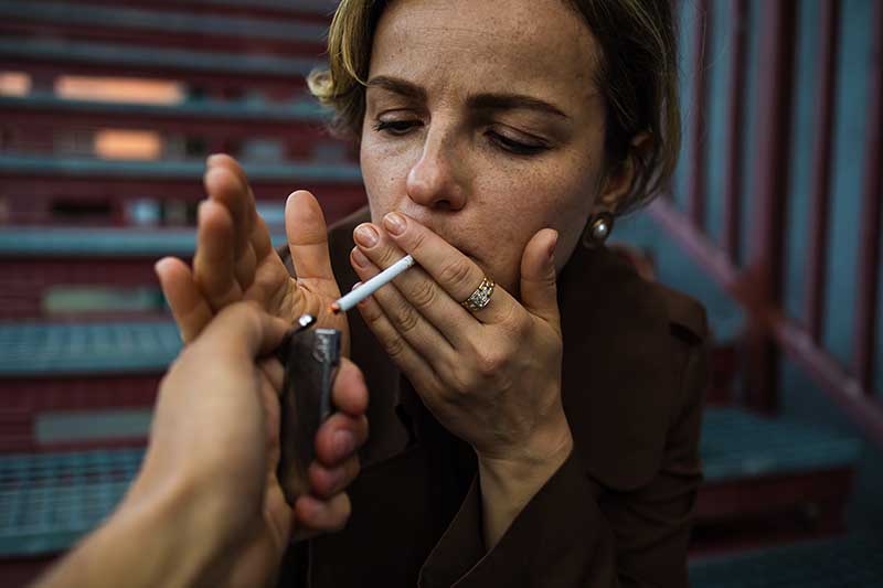 O femeie care isi aprinde tigara sa fumeze pentru ca nu poate renunta la fumat